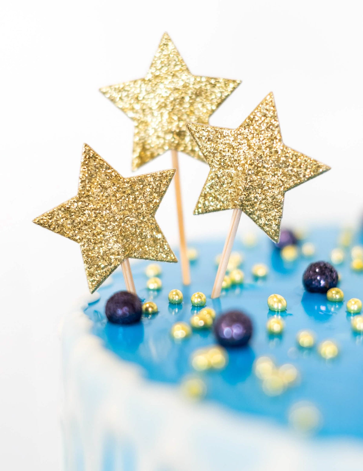 Krupni plan zlatnih šljokica cake toppera na štapu zvijezda za rođendan