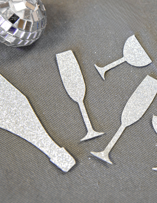 Gros plan sur la texture pailletée des confettis de table champagne argentés coupes et flûtes