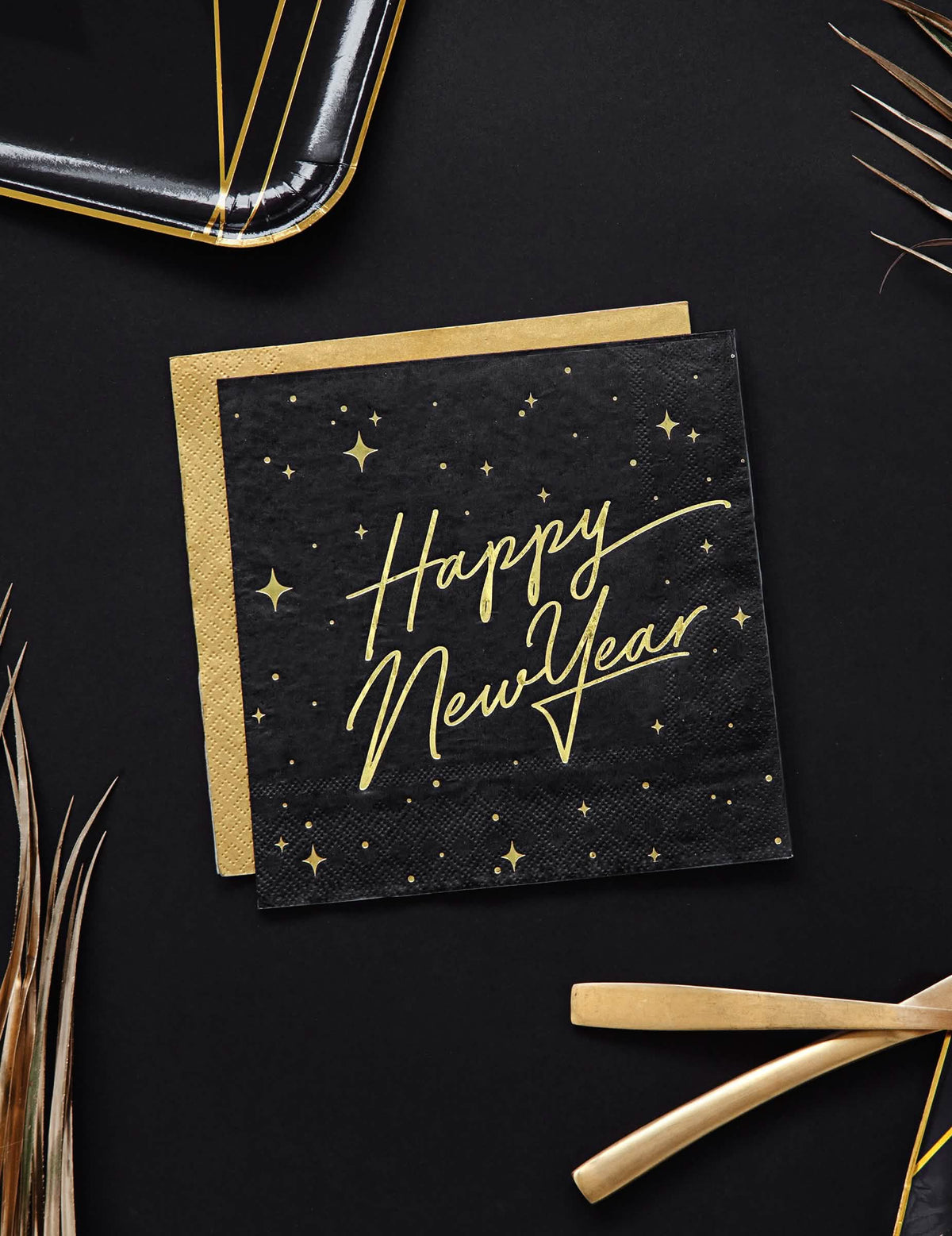 Pogled odozgo na crne i zlatne papirnate ubruse Happy New Year s ukrasom u obliku zvijezda
