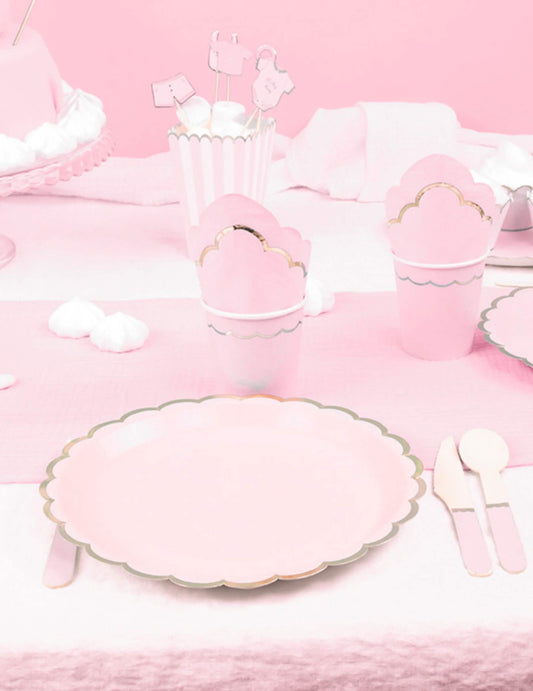 Mise en situation sur une table de fête des assiettes en carton festonnées rose pastel et or