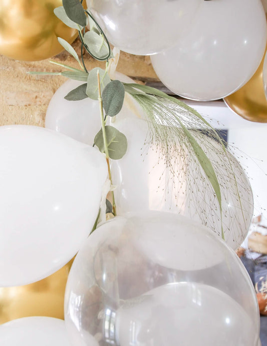 Gros plan sur la décoration végétale du kit arche de 60 ballons blanche et or avec eucalyptus végétale