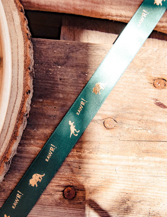 Gros plan sur les motifs du ruban en satin dinosaure et RAWR ! vert floqué or