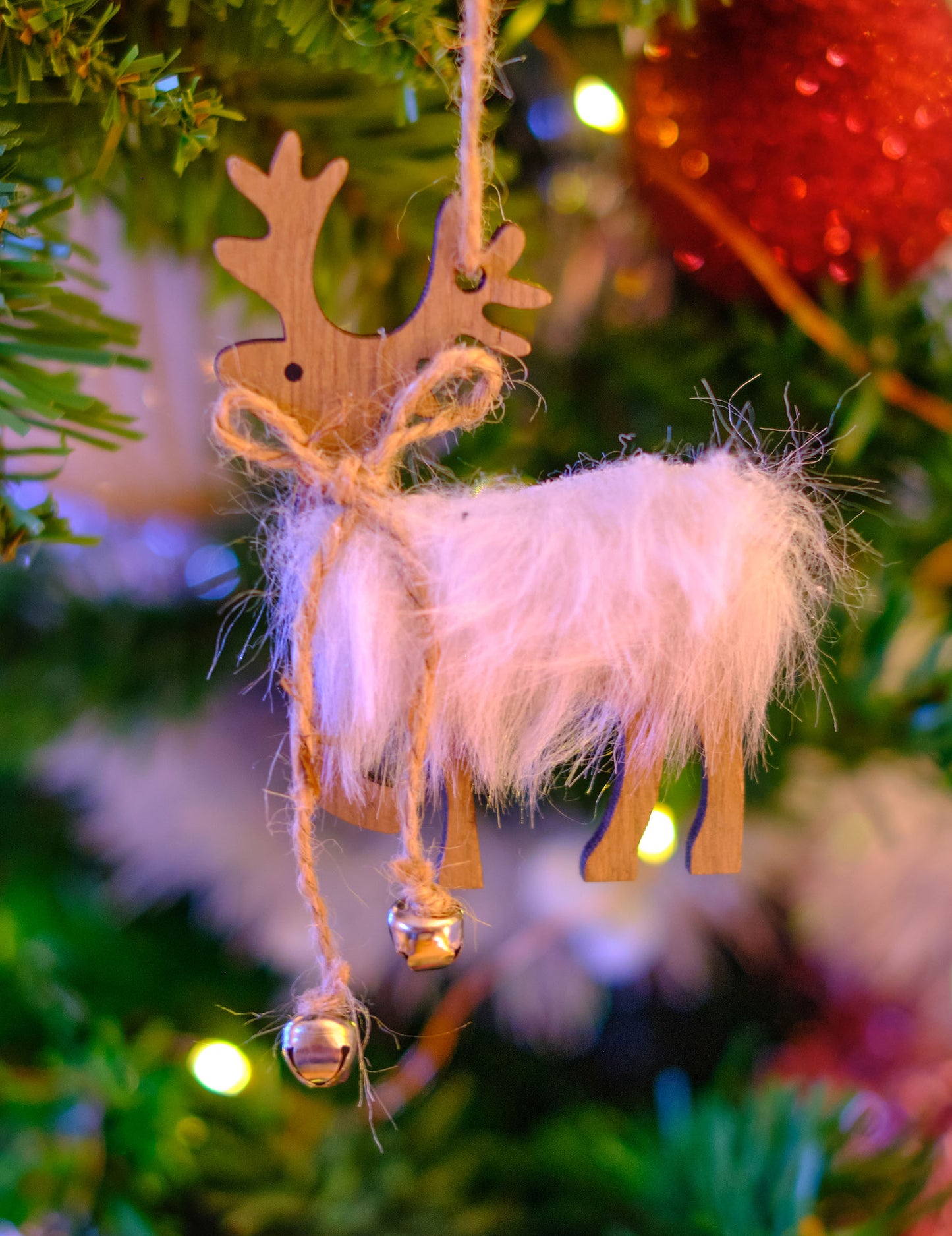 Gros plan sur la fourrure et les grelots de la suspension renne pour sapin en bois