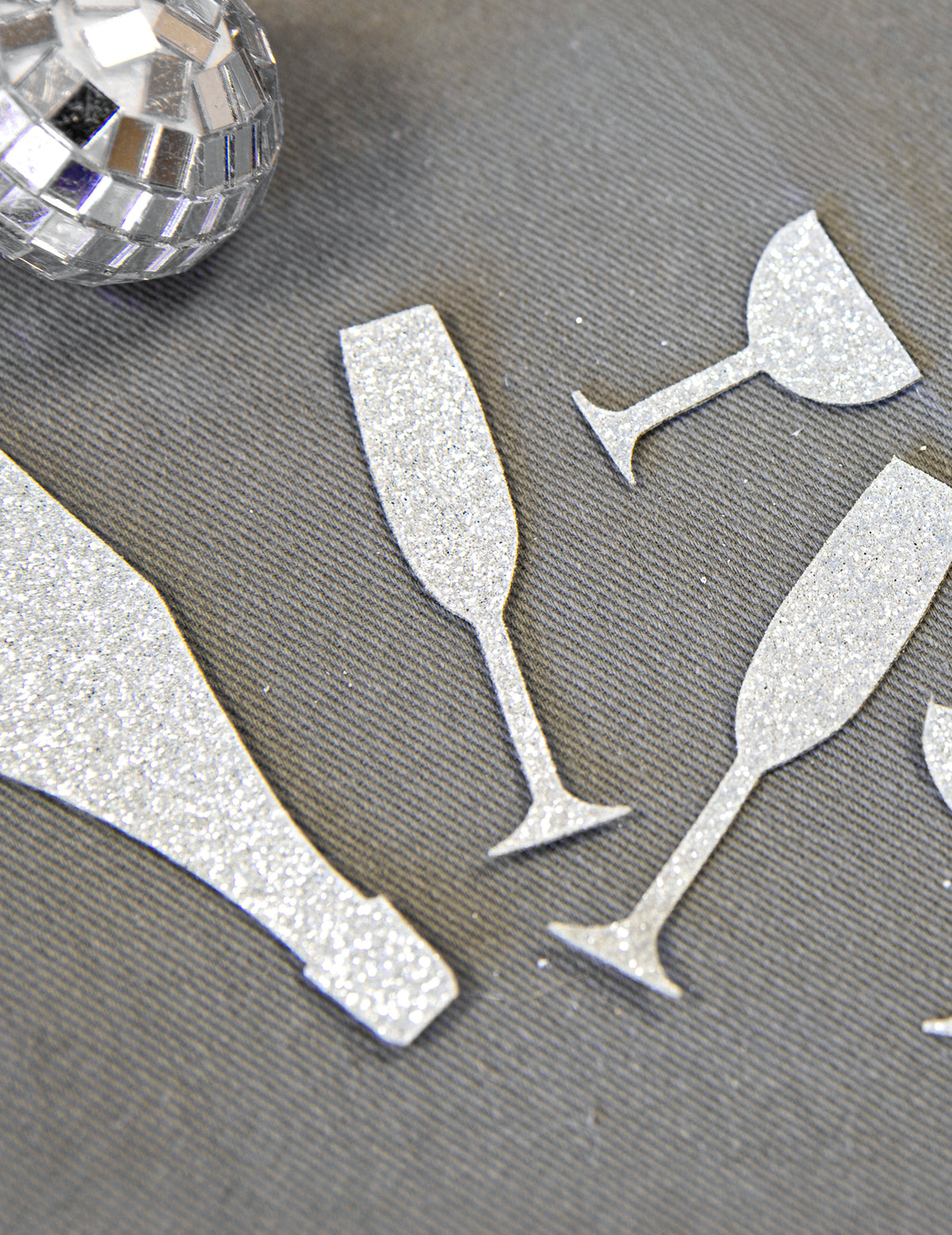 Gros plan sur la texture pailletée des confettis de table champagne argentés coupes et flûtes