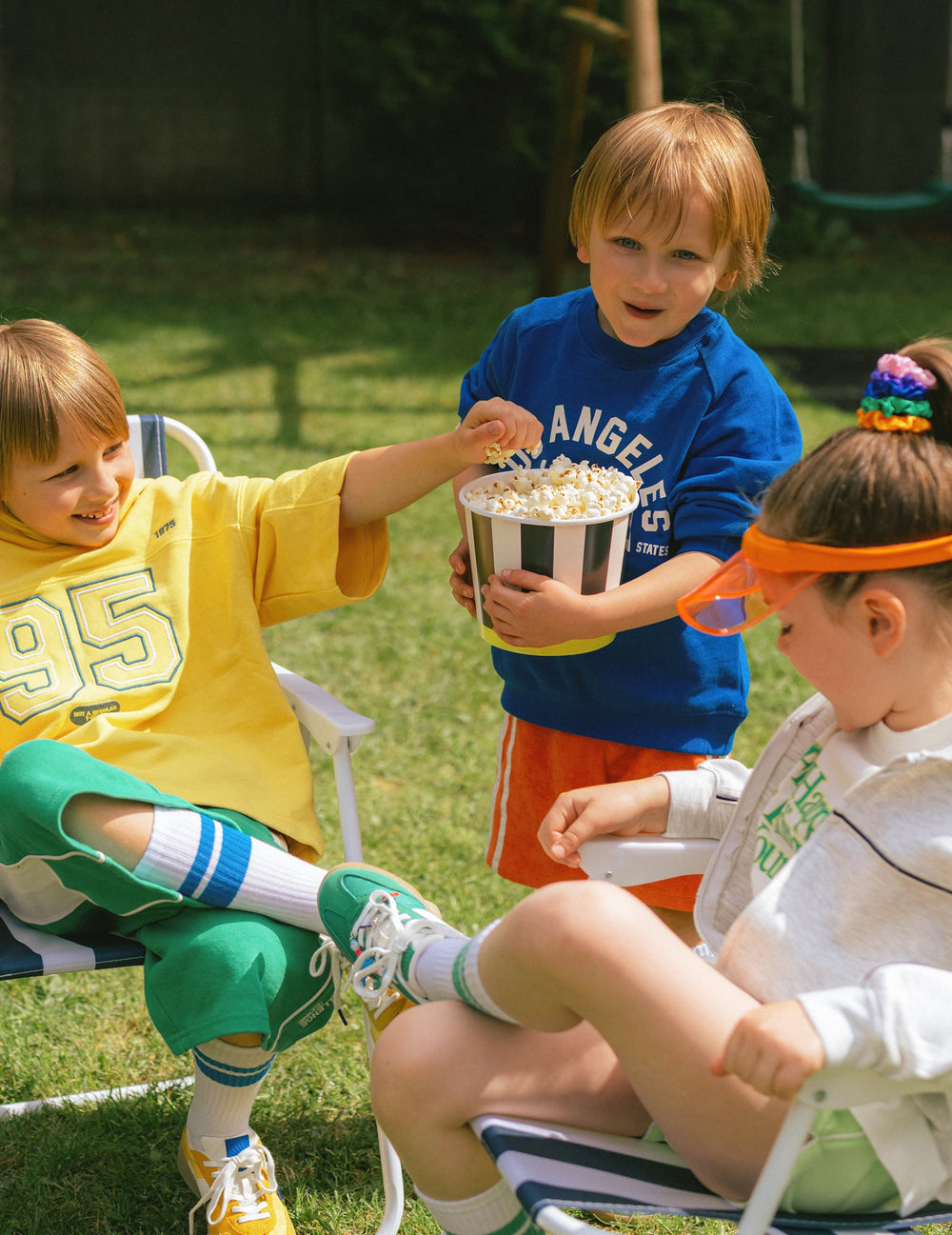 Enfants partageant du popcorn du pot à snacks en carton à rayures noires et blanches avec base jaune