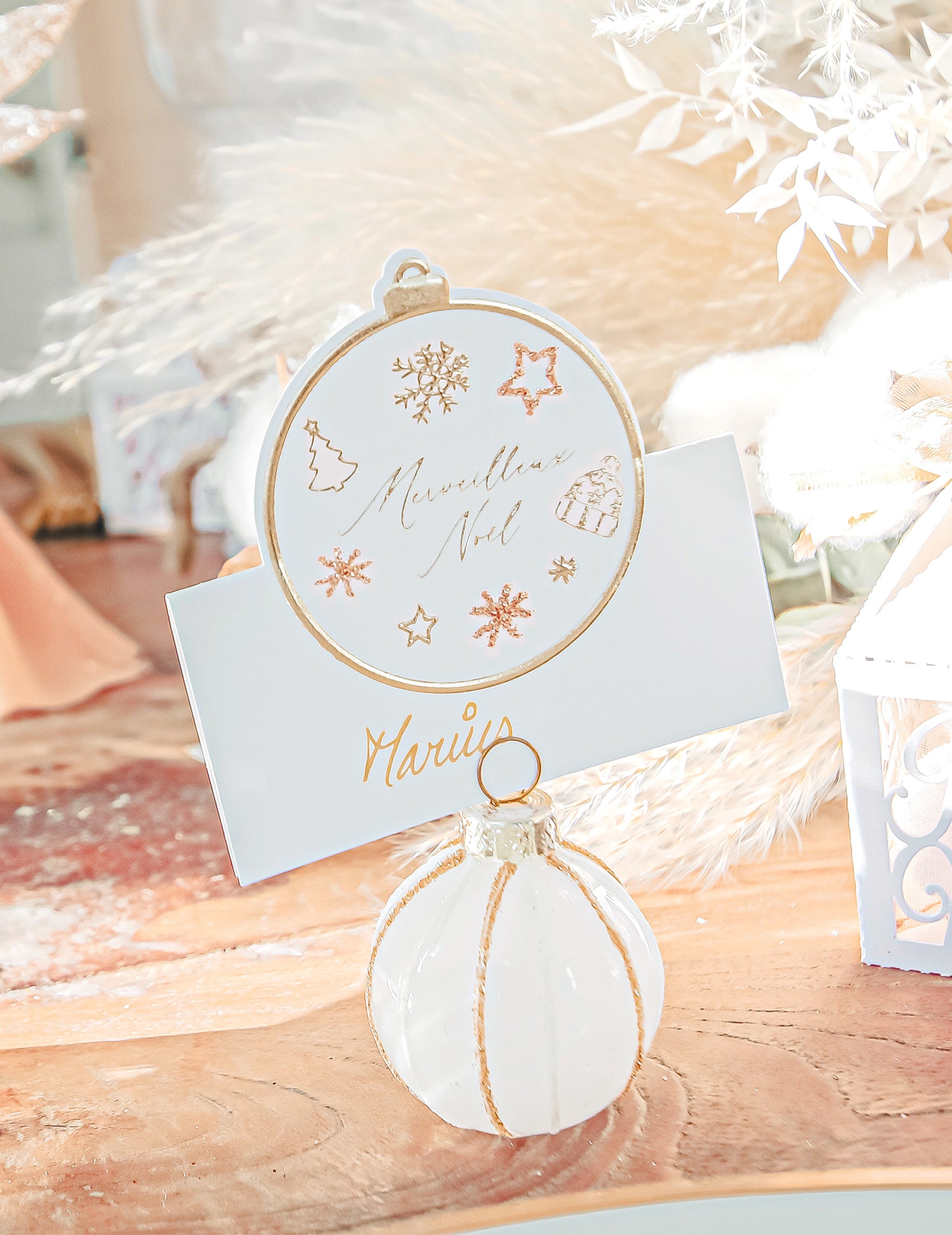 Gros plan sur la carte porte-nom du marque-place boule de Noël blanc et doré à paillettes