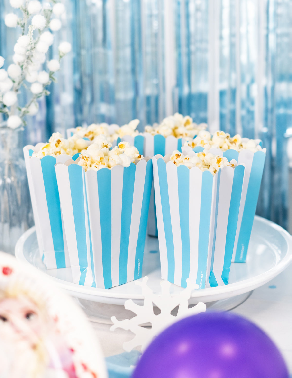 Mise en situation festive sur un plateau des boîtes à popcorn à rayures pour fête bleu et blanc turquoise