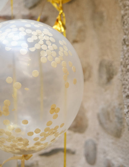 Gros plan sur les confettis du ballon en latex transparent avec confettis ocre doré