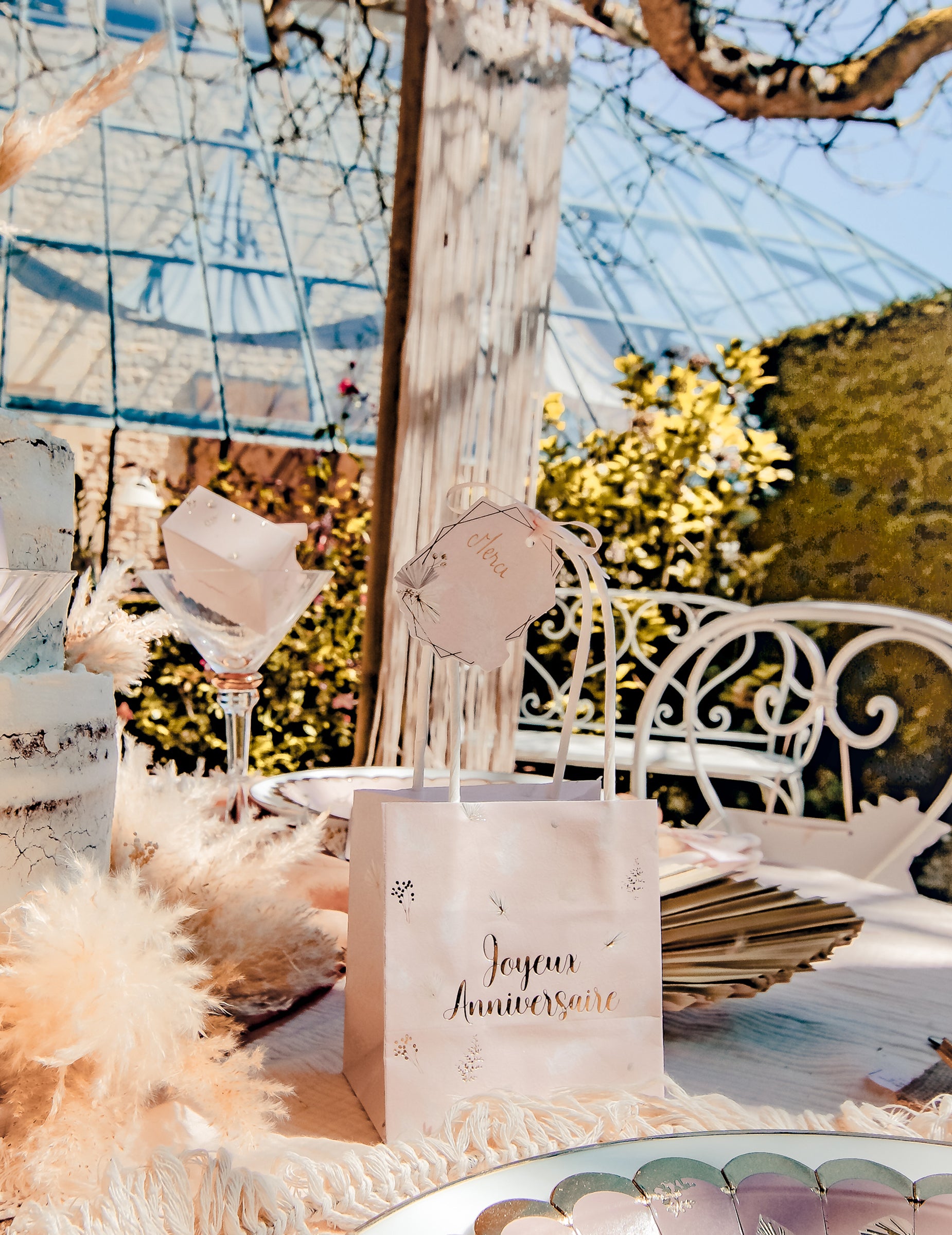 Mise en situation sur un sac cadeau des étiquettes boho pour décoration blush et or avec plumes et ruban