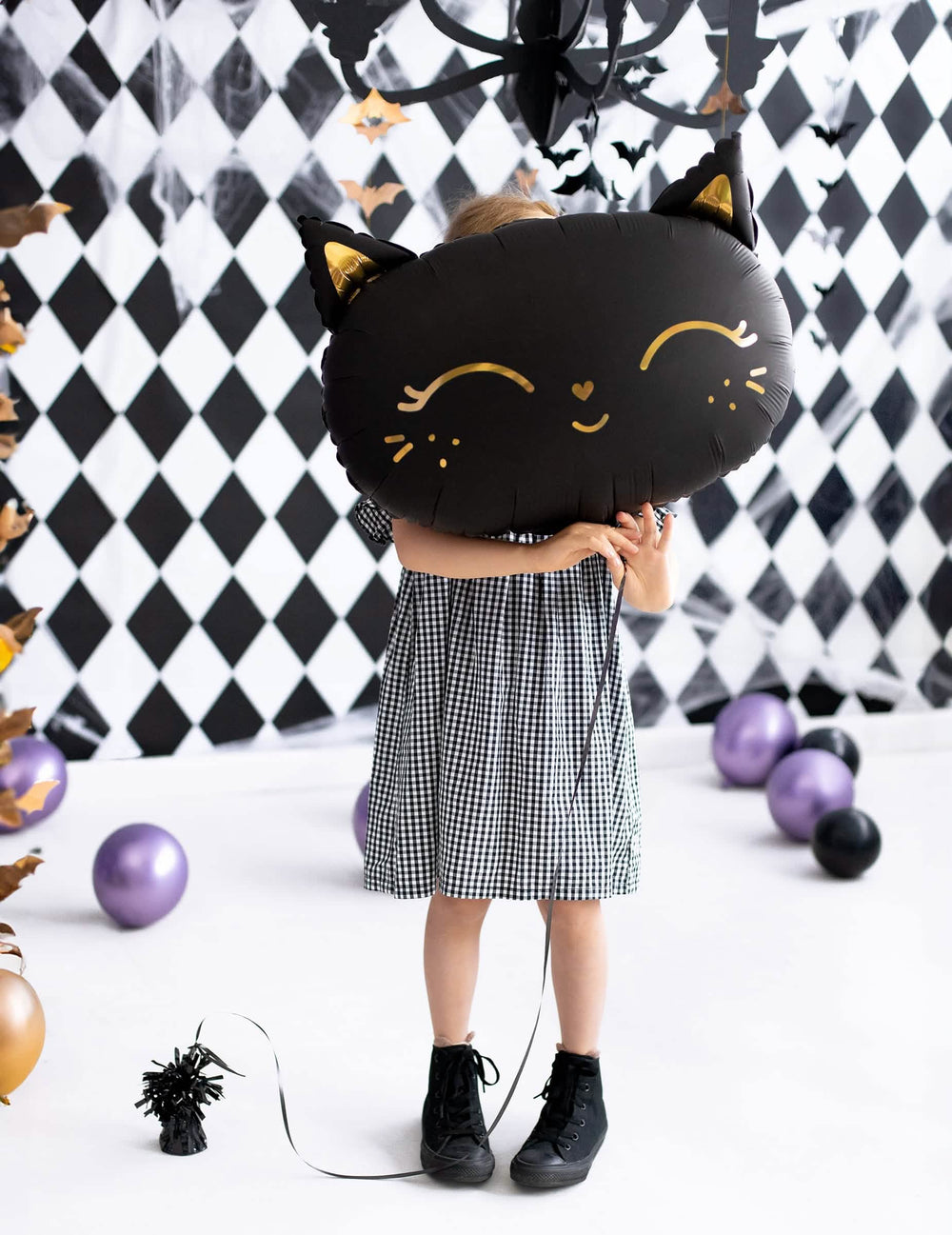 dijete drži ispred lica aluminijski balon mačke za halloween