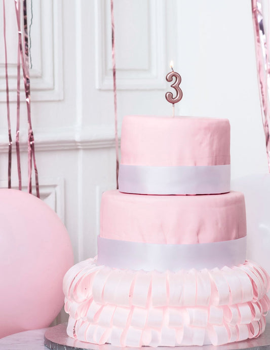 Mise en situation sur un gâteau de la bougie d'anniversaire chiffre 3 rose gold métallisée avec pic