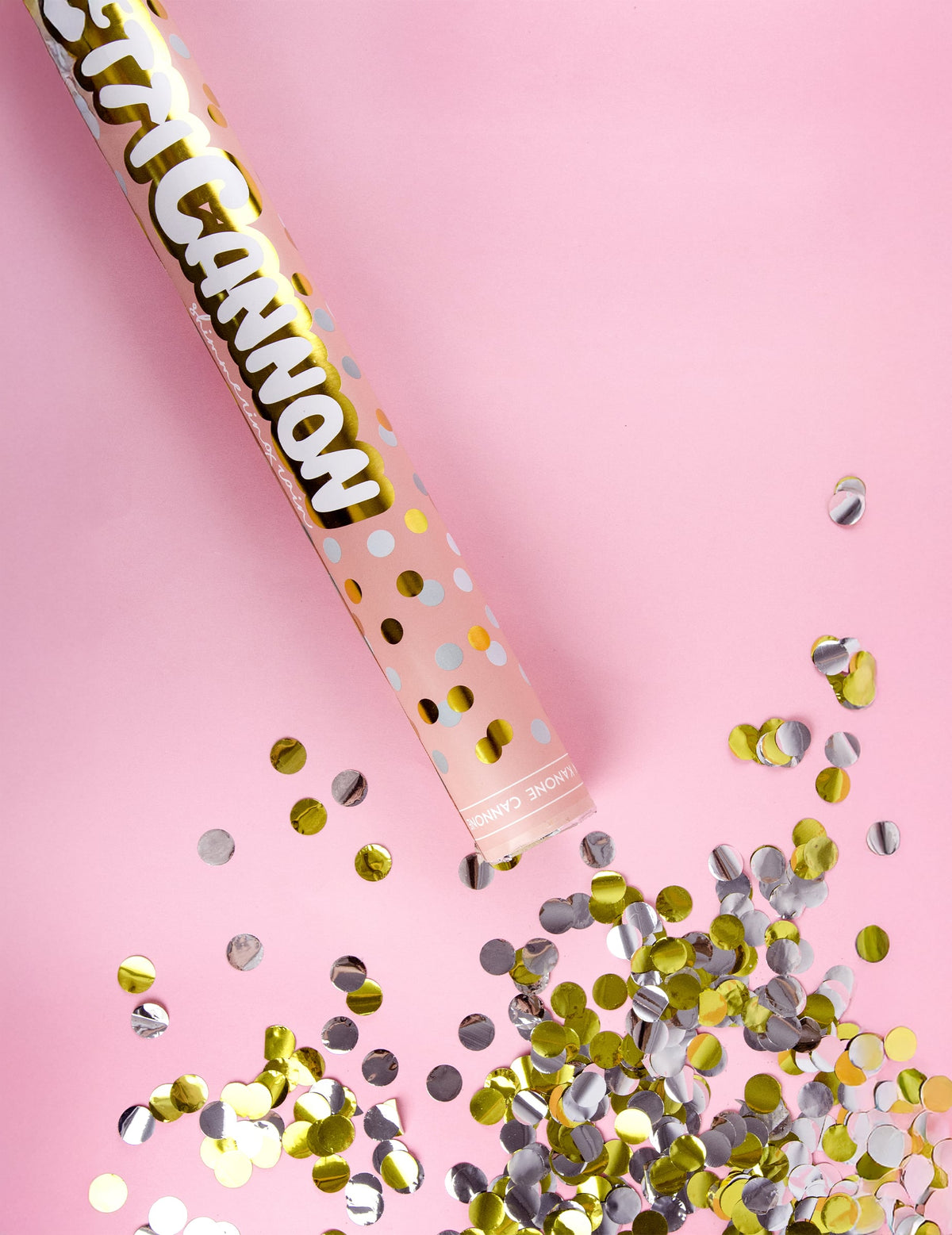 Mise en scène sur fond rose du canon à confettis or et argent
