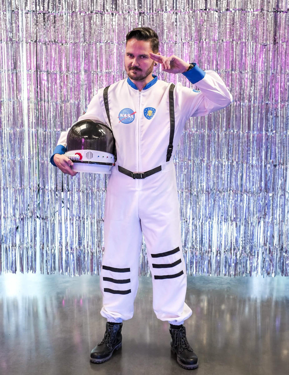 Poza s pozdravom s kacigom ispod ruke ispred srebrne pozadine kostima astronauti iz svemira