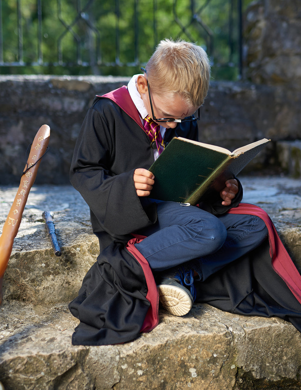 Mise en situation avec livre et baguette du déguisement Harry Potter™ pour enfant