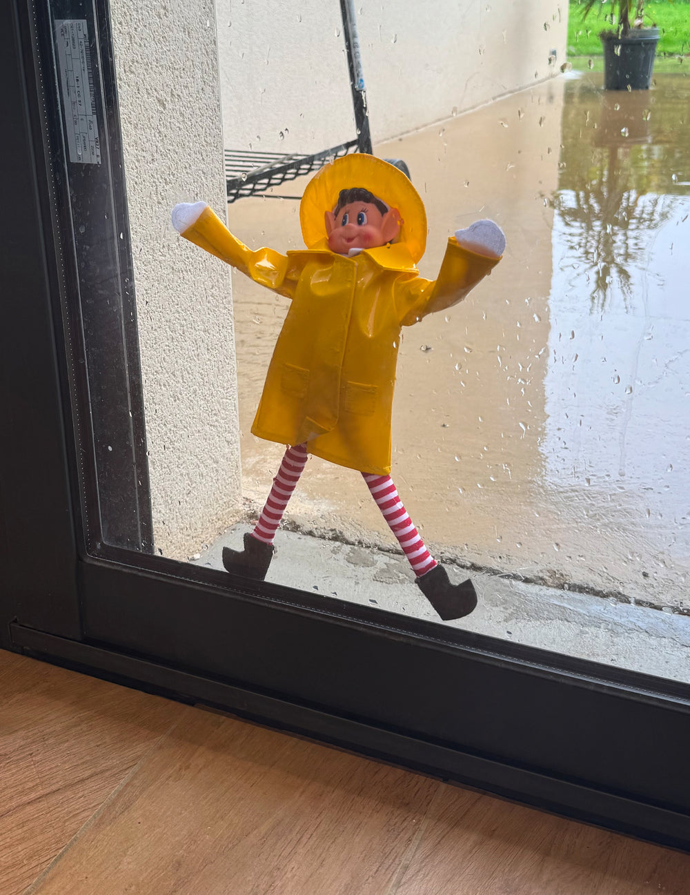 Mise en scène sur une vitre pluvieuse du déguisement imperméable de lutin farceur pour poupée