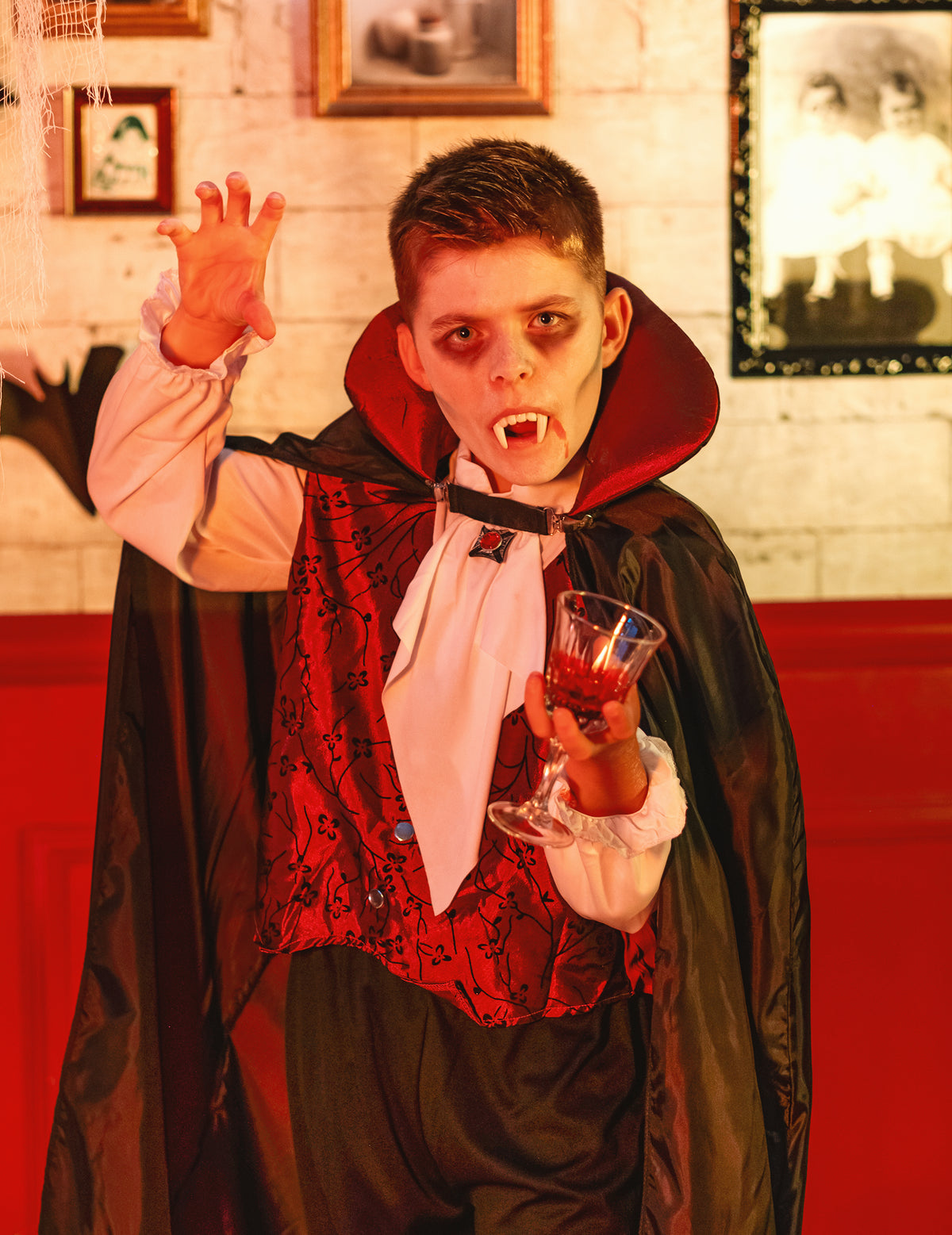 Mise en situation avec dents de vampire et verre du déguisement vampire élégant pour garçon