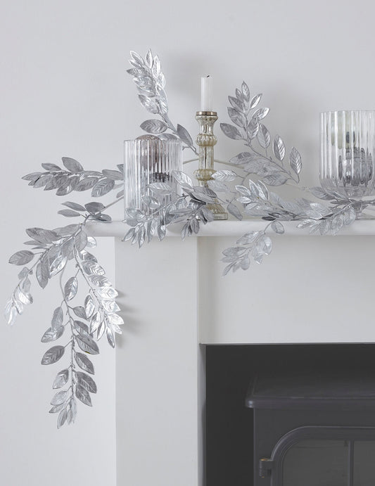 Mise en situation sur une cheminée de la guirlande de feuillages de Noël pour table argentée