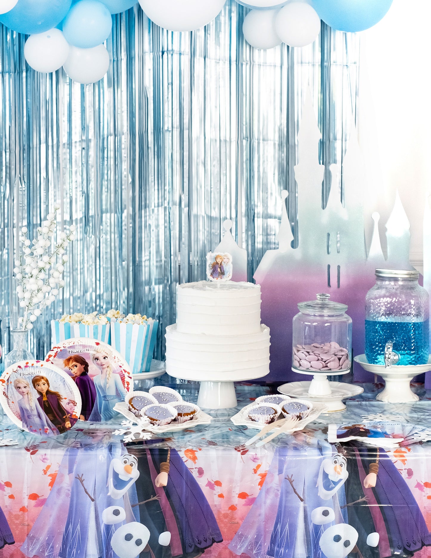 Mise en scène d'un buffet d'anniversaire avec la nappe en plastique La Reine des Neiges 2