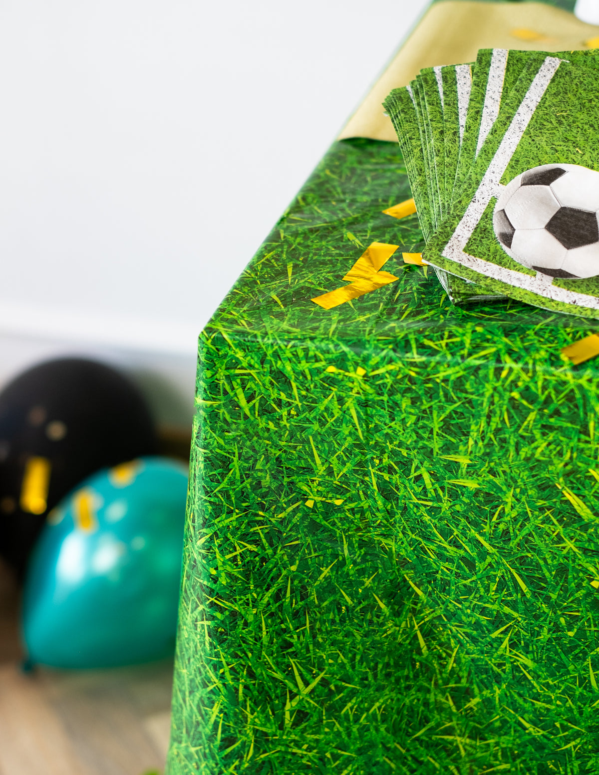 Détail du coin et des serviettes football de la nappe effet herbe verte en plastique