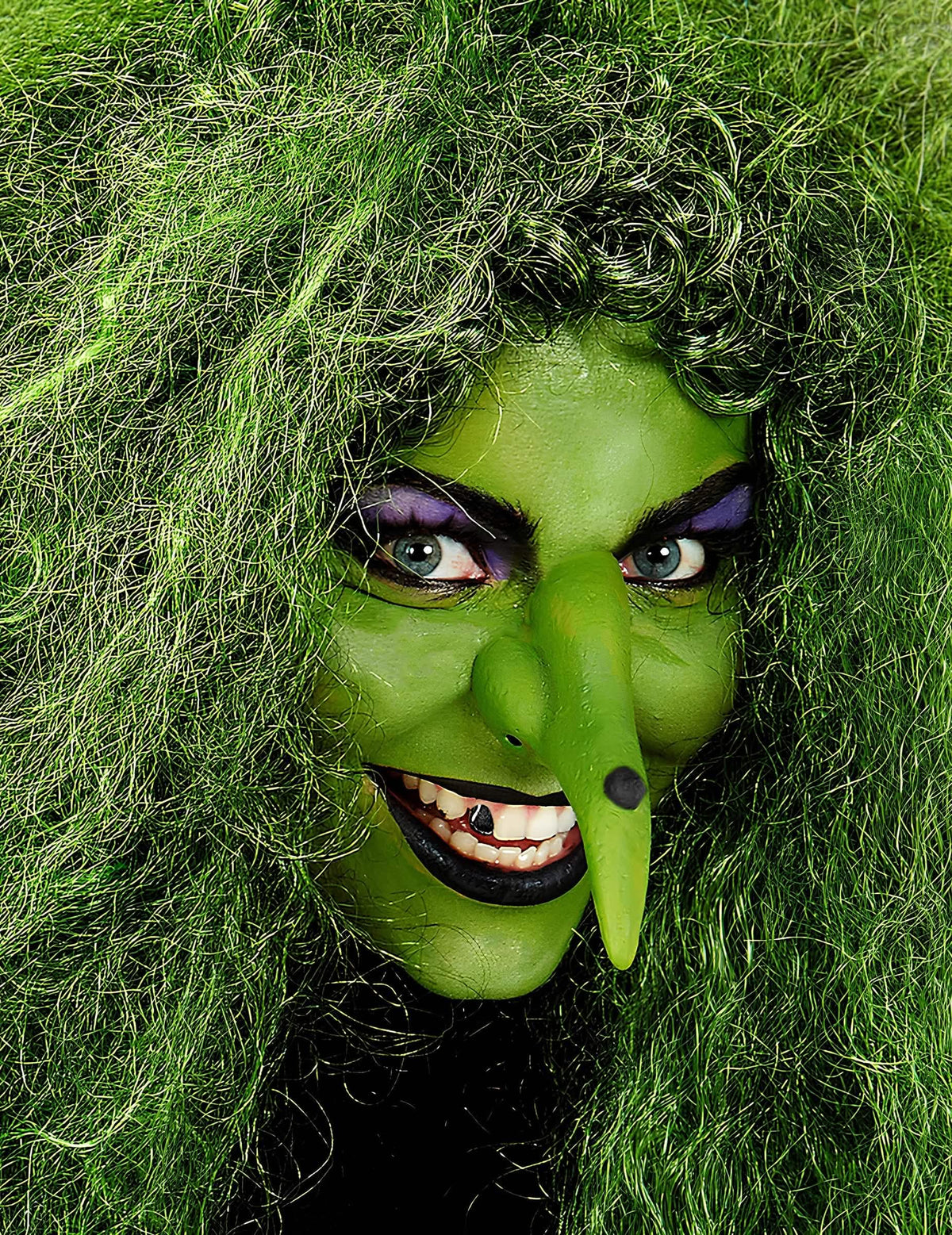 Gros plan sur le visage maquillé en sorcière du maquillage professionnel à l'eau pour visage et corps vert