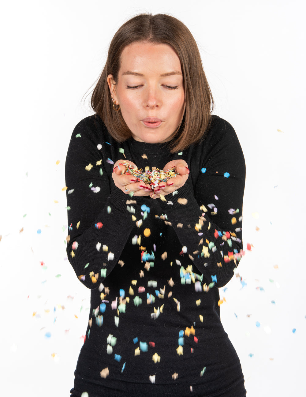 Femme soufflant les confettis du sachet de confettis de carnaval pour fête