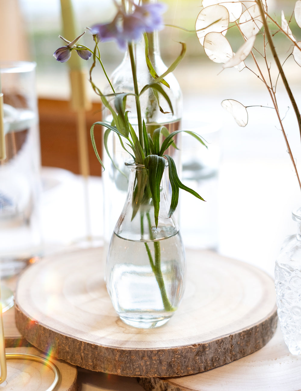 Gros plan sur le vase soliflore en verre pour décoration de table sur rondelle de bois